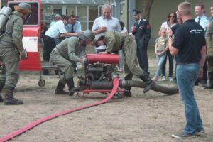 Feuerwehrmänner bei einer Übung, Schlauch und Gerät im Einsatz.