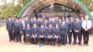 Ein Gruppenfoto von Mitgliedern in Uniform, davor ein Mann in Zivil.