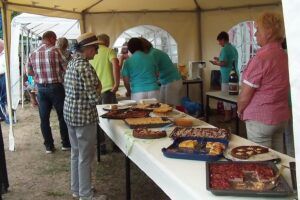 Ein Mann und eine Frau betrachten ein Buffet, während andere Personen im Hintergrund stehen.