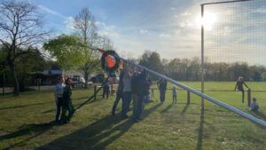 Kinder trainieren auf einem Sportplatz im Freien. Ein großes Netz spannt sich vor ihnen.