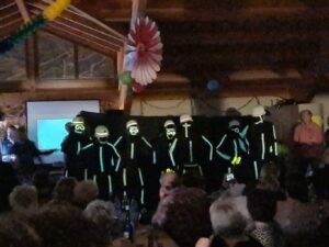 Eine Gruppe von Tanzern in schwarzen Kostümen mit grünen Streifen