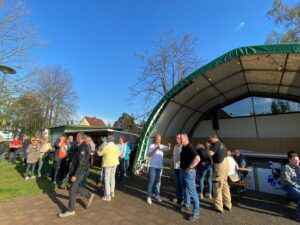 Menschen stehen vor einer Zelthalle und unterhalten sich