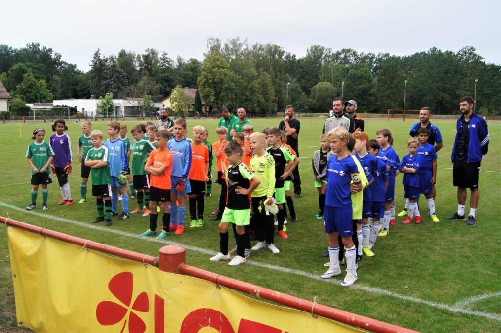Gruppe von Kindern in verschiedenen Fußballtrikots auf einem Sportplatz