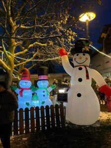 Ein großer aufblasbarer Schneemann neben drei kleineren beleuchteten Schneemännern