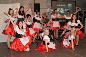 Eine Gruppe von Tänzern in traditioneller deutscher Kleidung. Sie tragen weiße und rote Outfits.