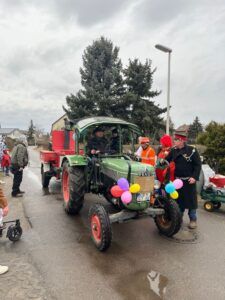 Ein grüner Traktor mit roten Rädern und Ballons