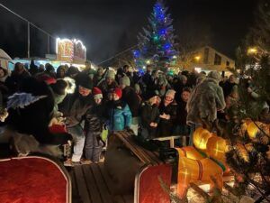 Menschenmenge auf einem Weihnachtsmarkt, im Hintergrund ein Weihnachtsbaum.